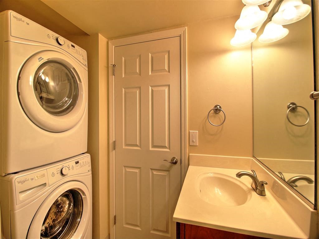 a white washer and dryer in a bathroom with a sink and a door