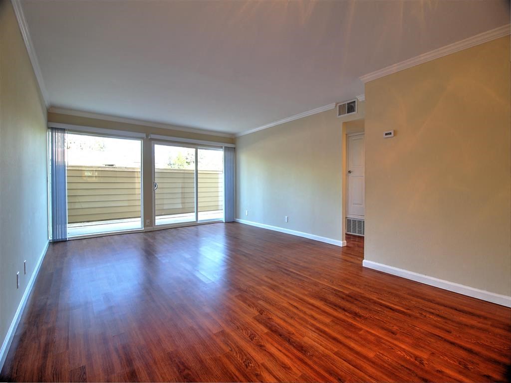 an empty living room with wood floors and sliding glass doors