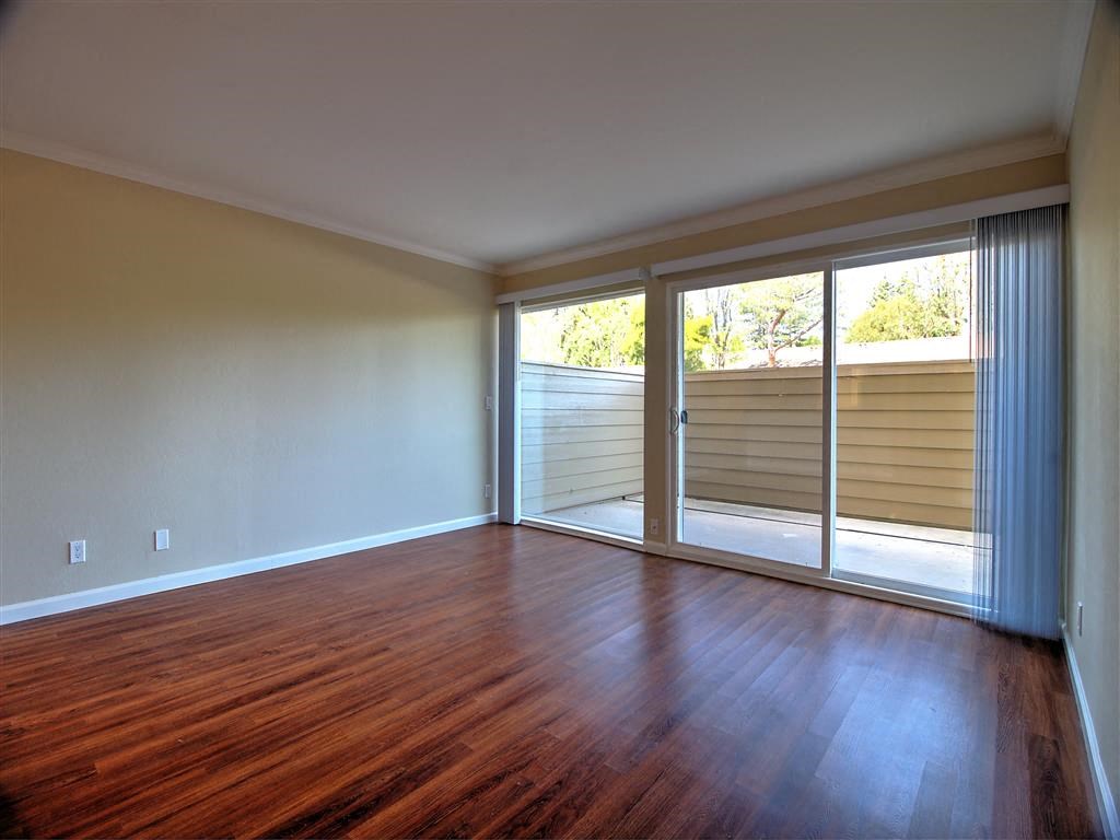 an empty living room with wood floors and sliding glass doors