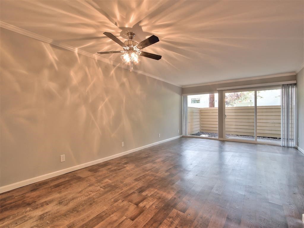 an empty living room with a ceiling fan and a window