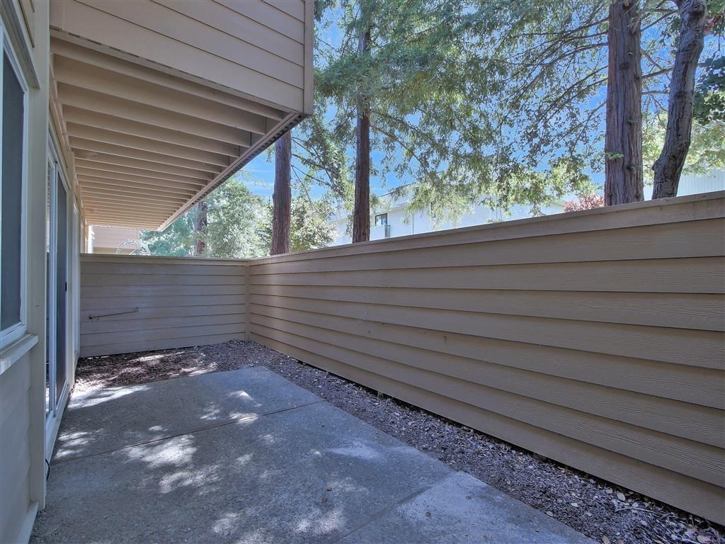 the side of a house with a patio and trees