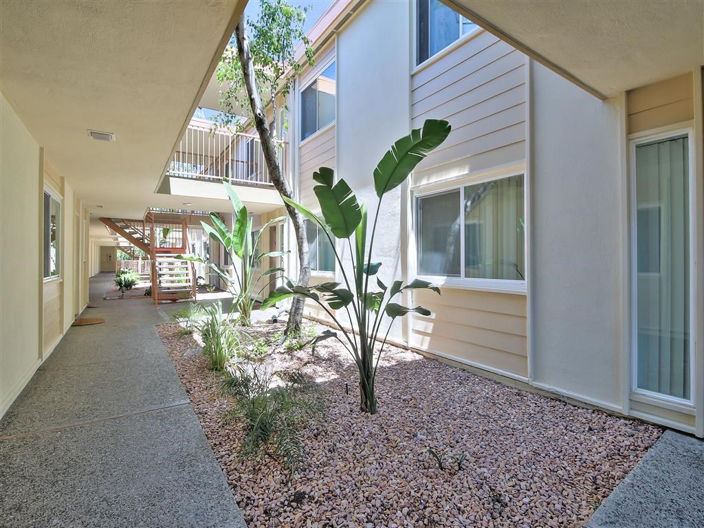 a long walkway with plants in front of a building