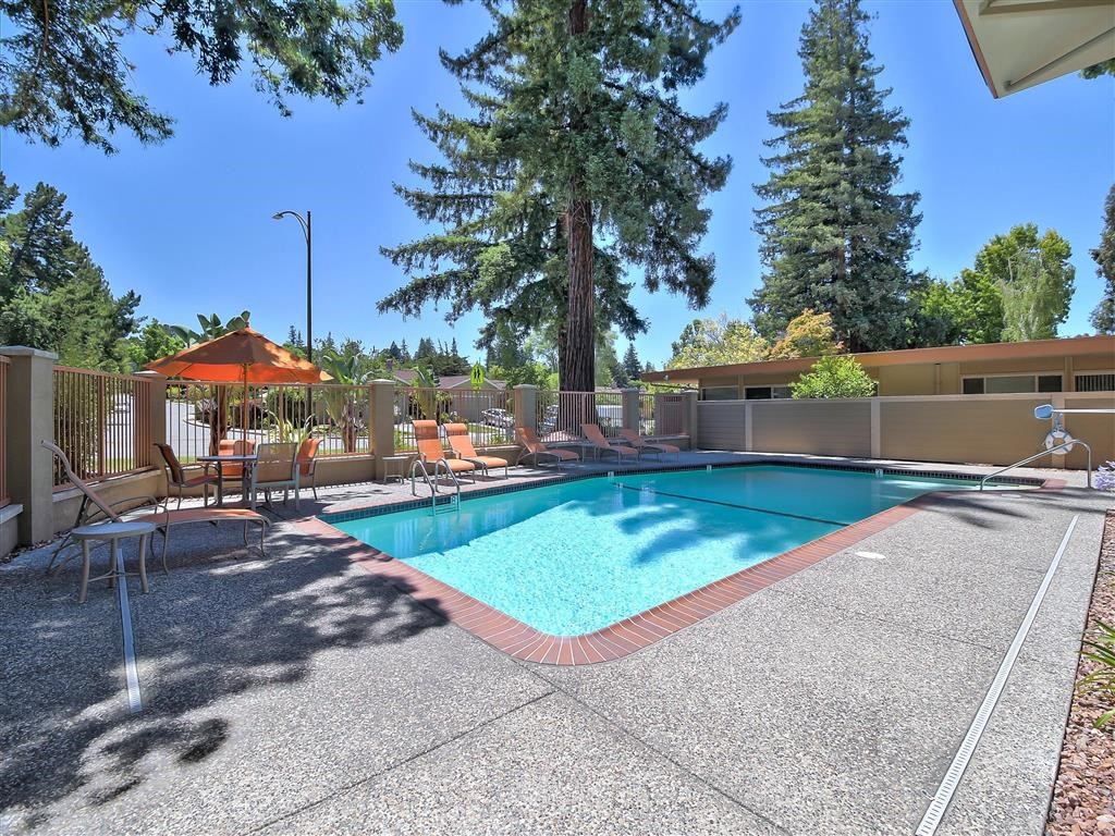 a resort style swimming pool with chairs and tables around it