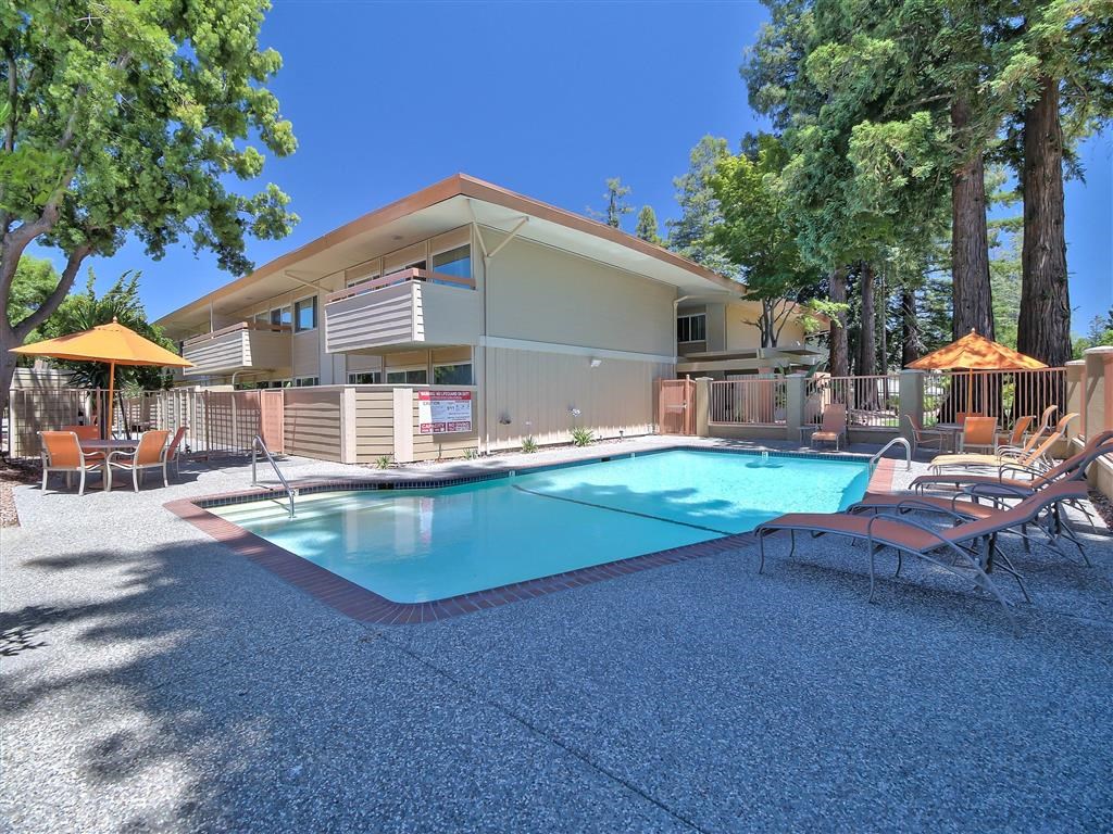 a pool with chairs and a building in the background