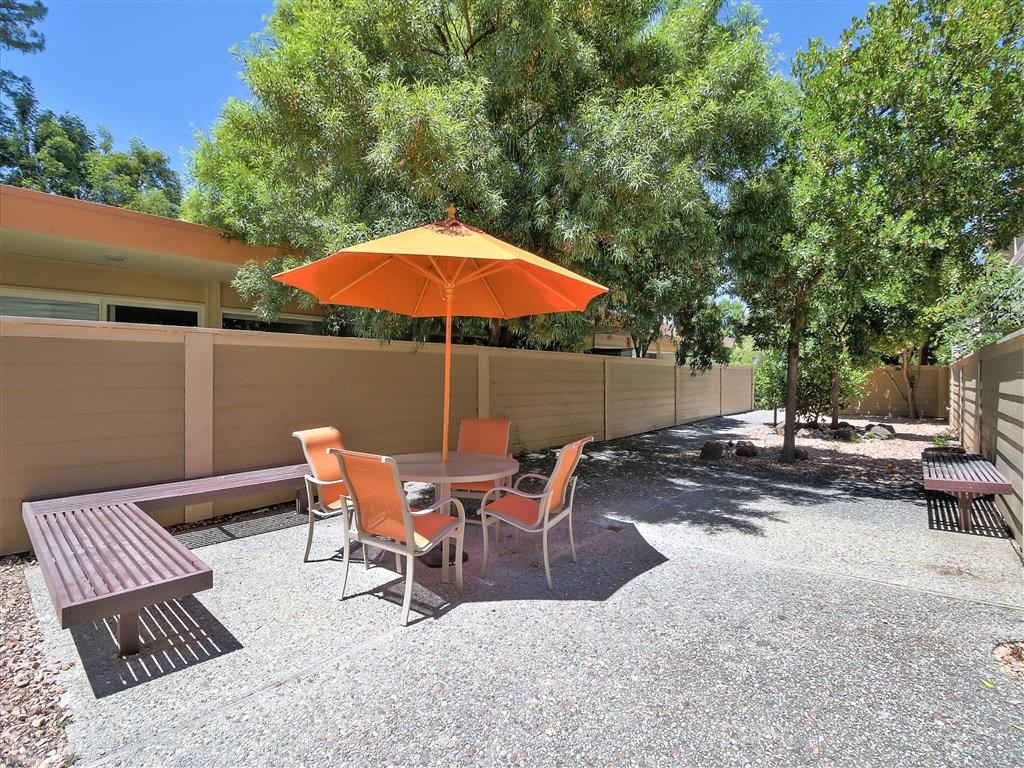 a patio with an orange umbrella and a table and chairs