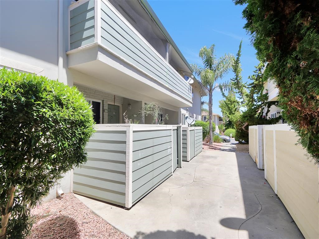 A white building with a green roof and a white fence.