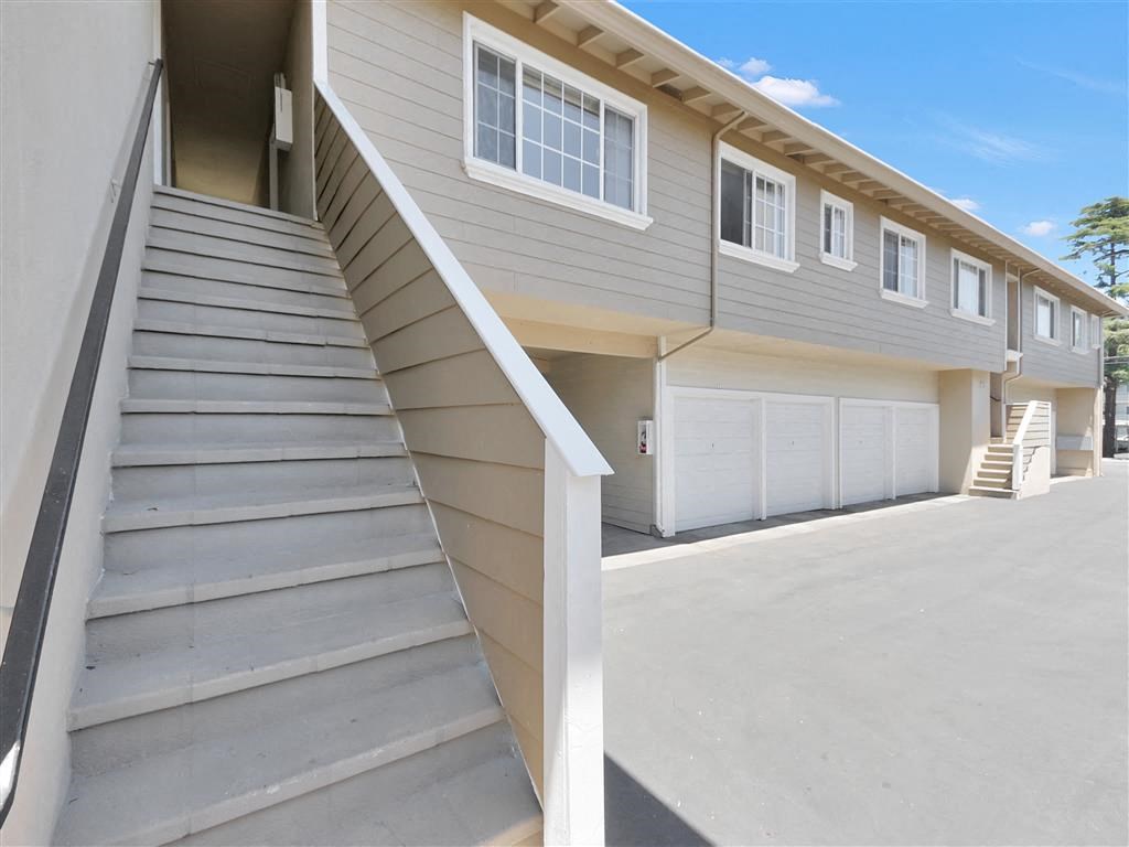 a gray house with stairs and a garage next to it