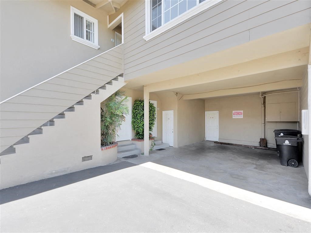 an empty parking garage with stairs and a white building