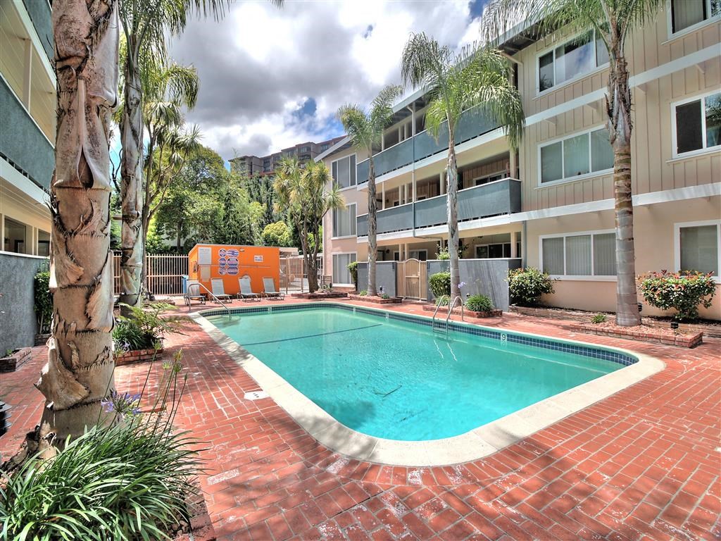 a swimming pool in front of a building with palm trees
