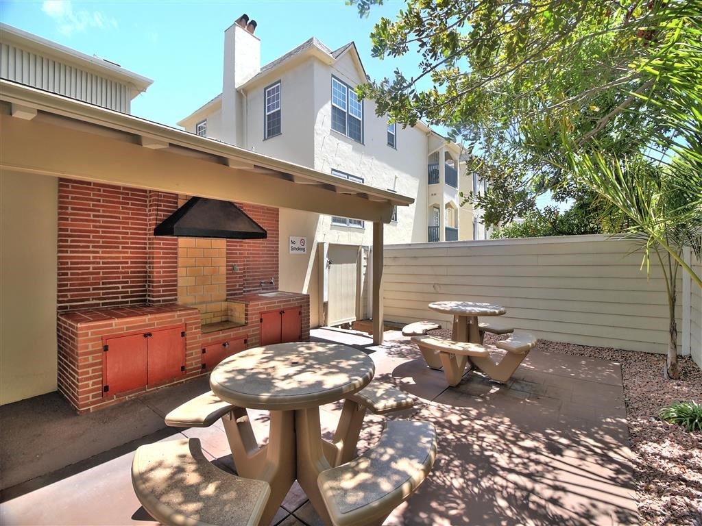 a backyard with a barbecue grill and tables