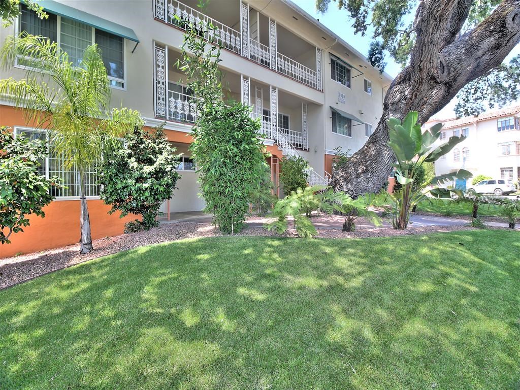 an apartment building with a lawn and trees in front of it