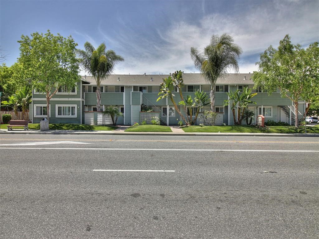 A street view of a building with a green facade and trees in front.