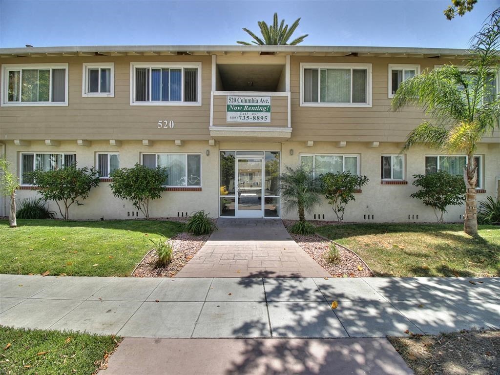 the front of an apartment building with a walkway and grass