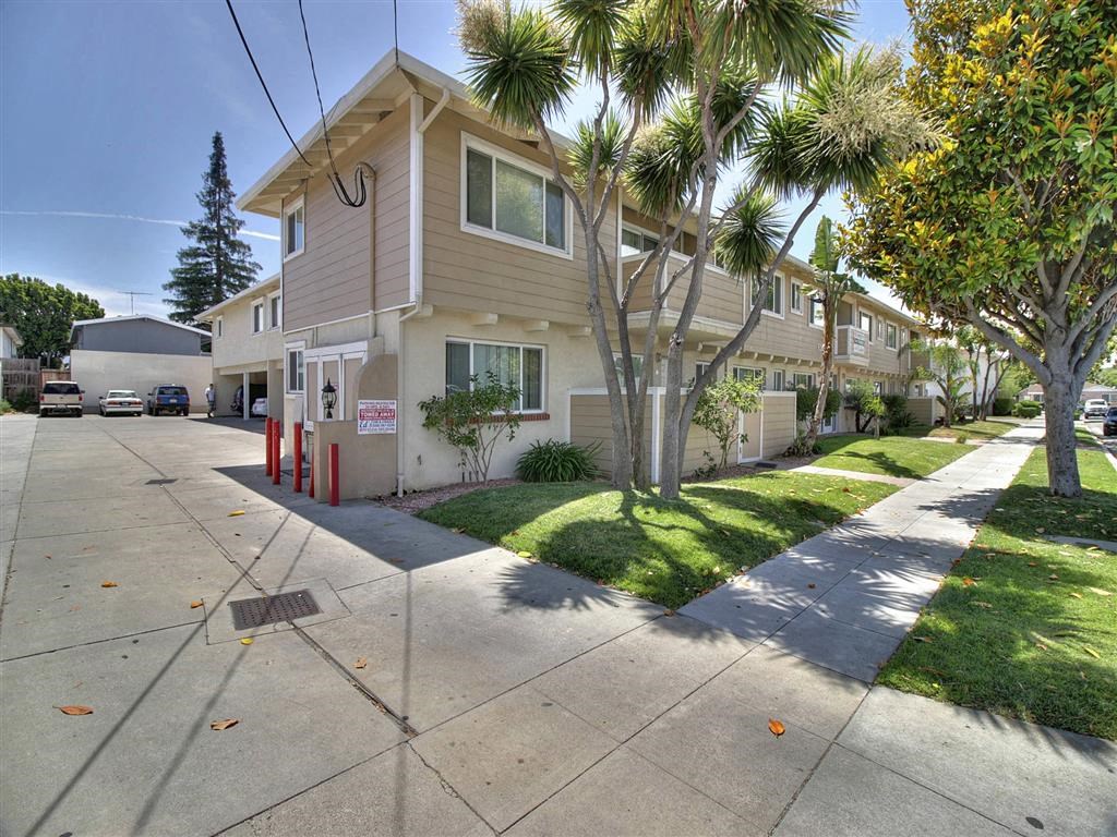 a beige house with a sidewalk and palm trees