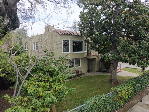 A house with a green lawn and trees in front.