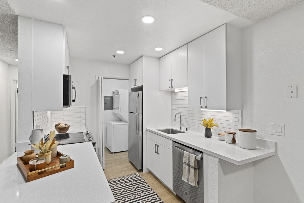 a kitchen with white cabinets and a white counter top and a stainless steel refrigerator