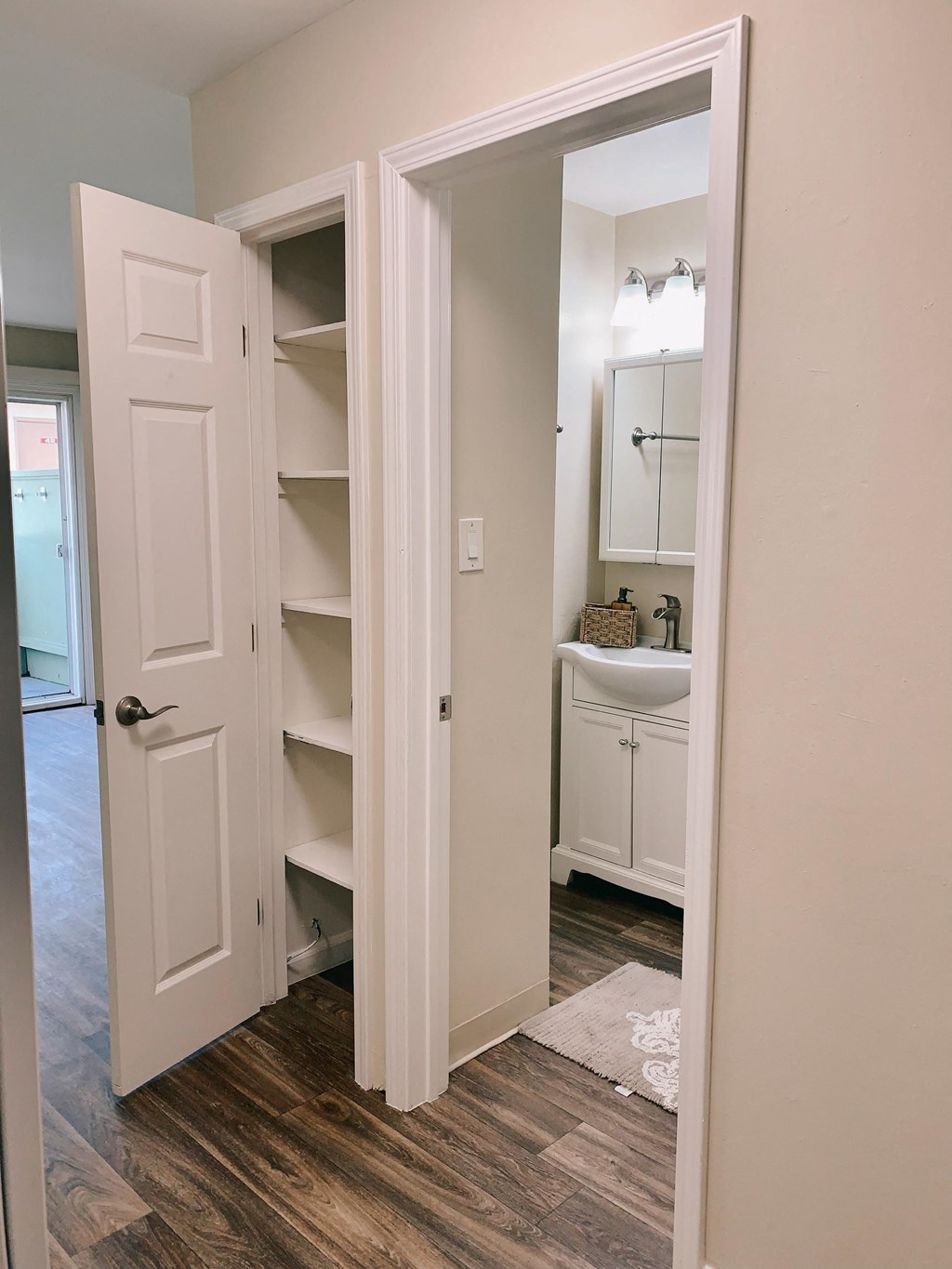 a bathroom with an open door and a sink and shelves