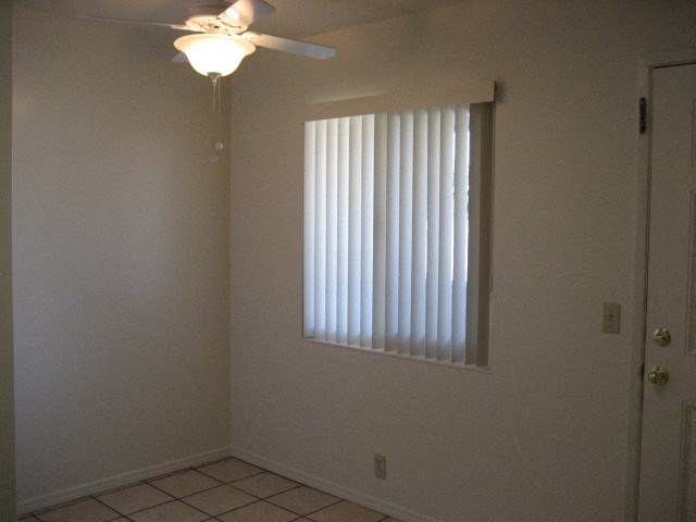 A room with a ceiling fan and a window with blinds.
