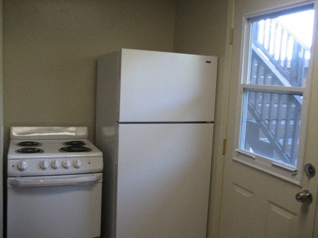 A white stove and refrigerator in a small kitchen.