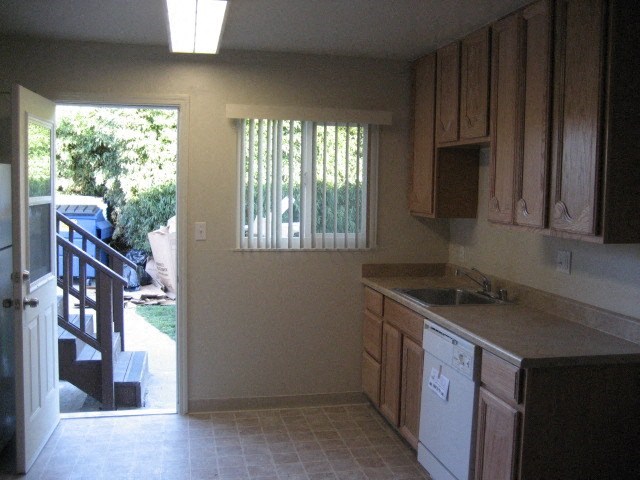 A kitchen with a dishwasher and wooden cabinets.