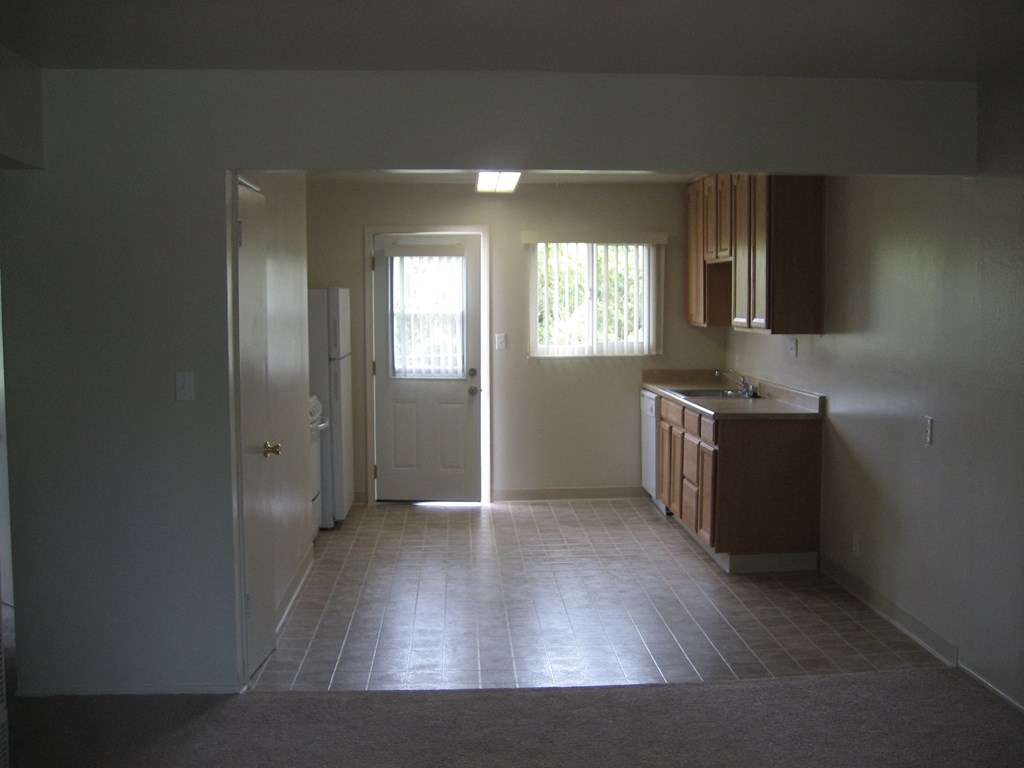 A kitchen with a sink, cabinets, and a window.