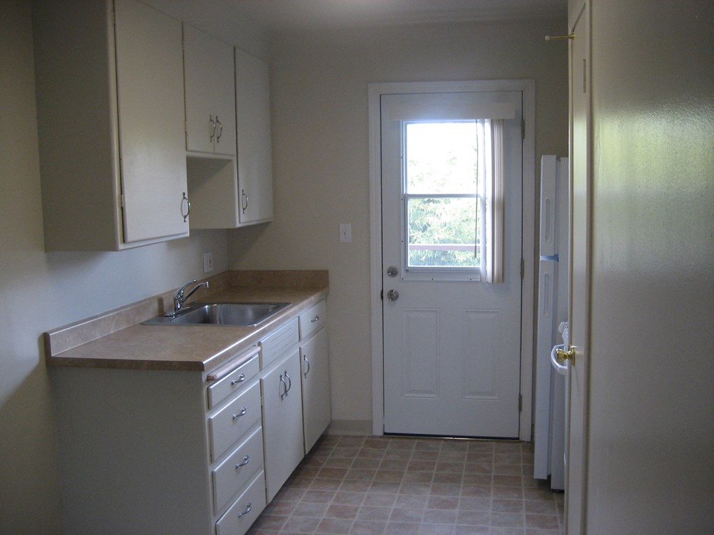 A kitchen with white cabinets and a white door.