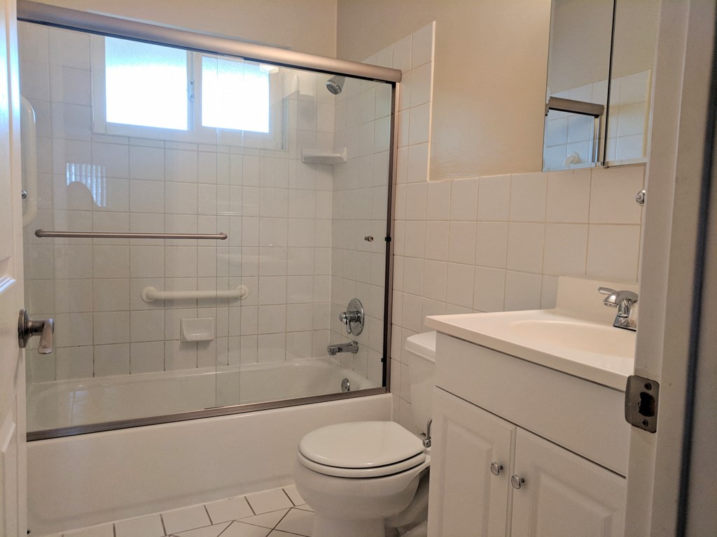 a white bathroom with a shower toilet and sink