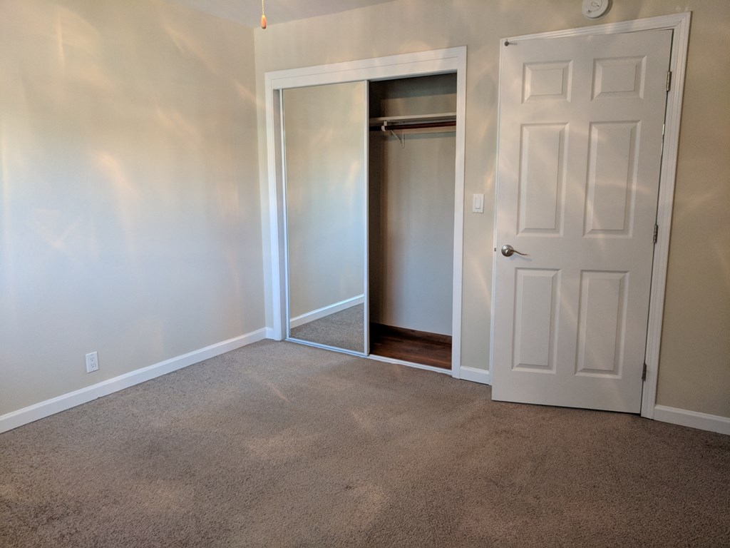 an empty room with a white door and a closet