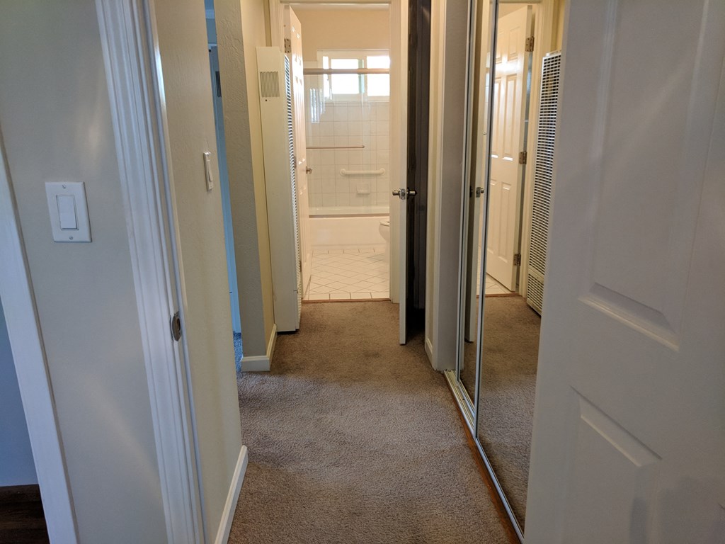 a view of the hallway from the closet into the bathroom and the shower