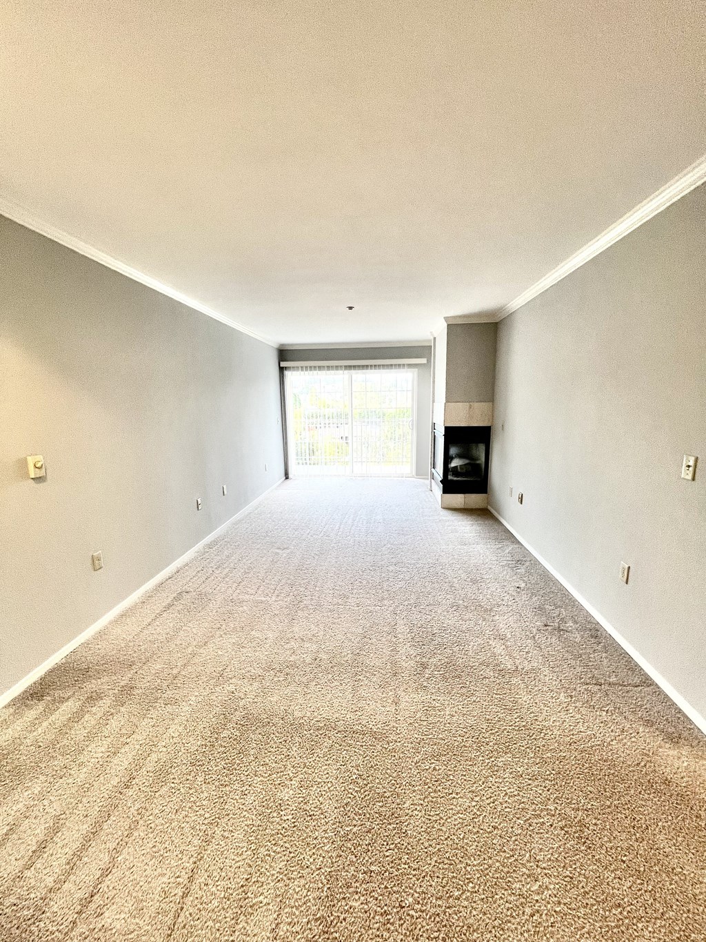 A long hallway with a carpeted floor and a door at the end.