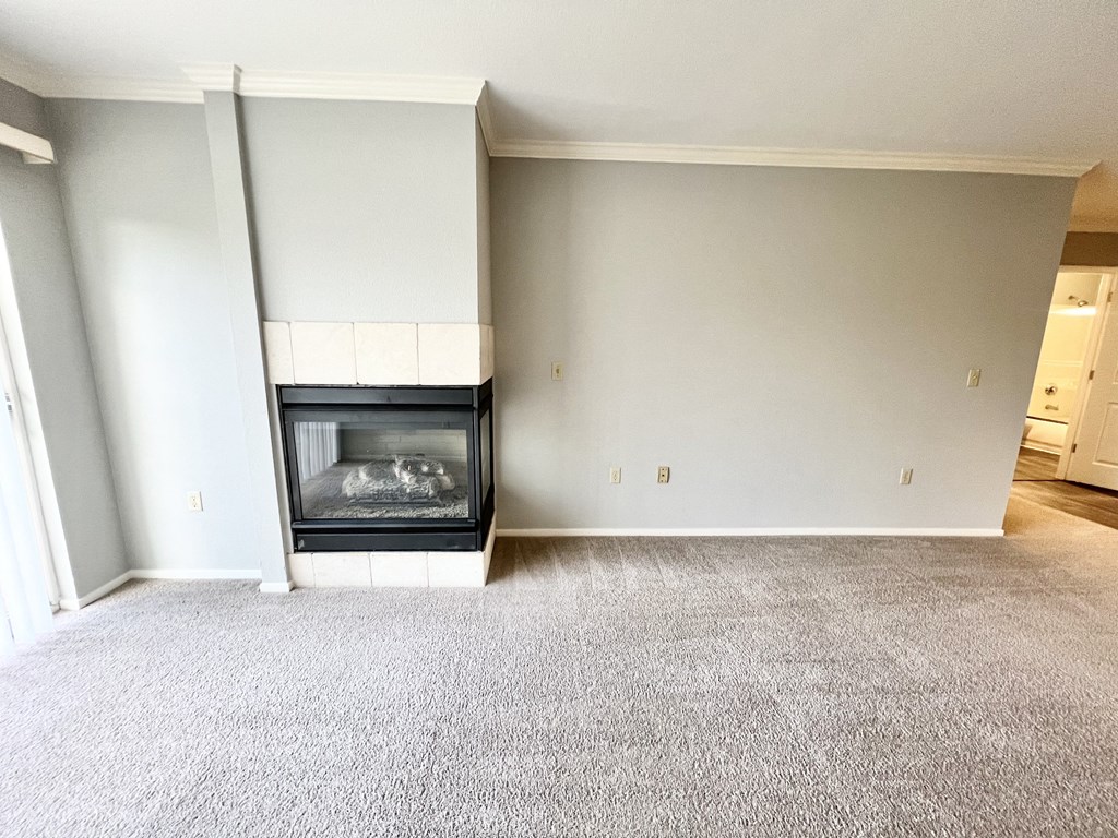 A living room with a fireplace and grey carpet.