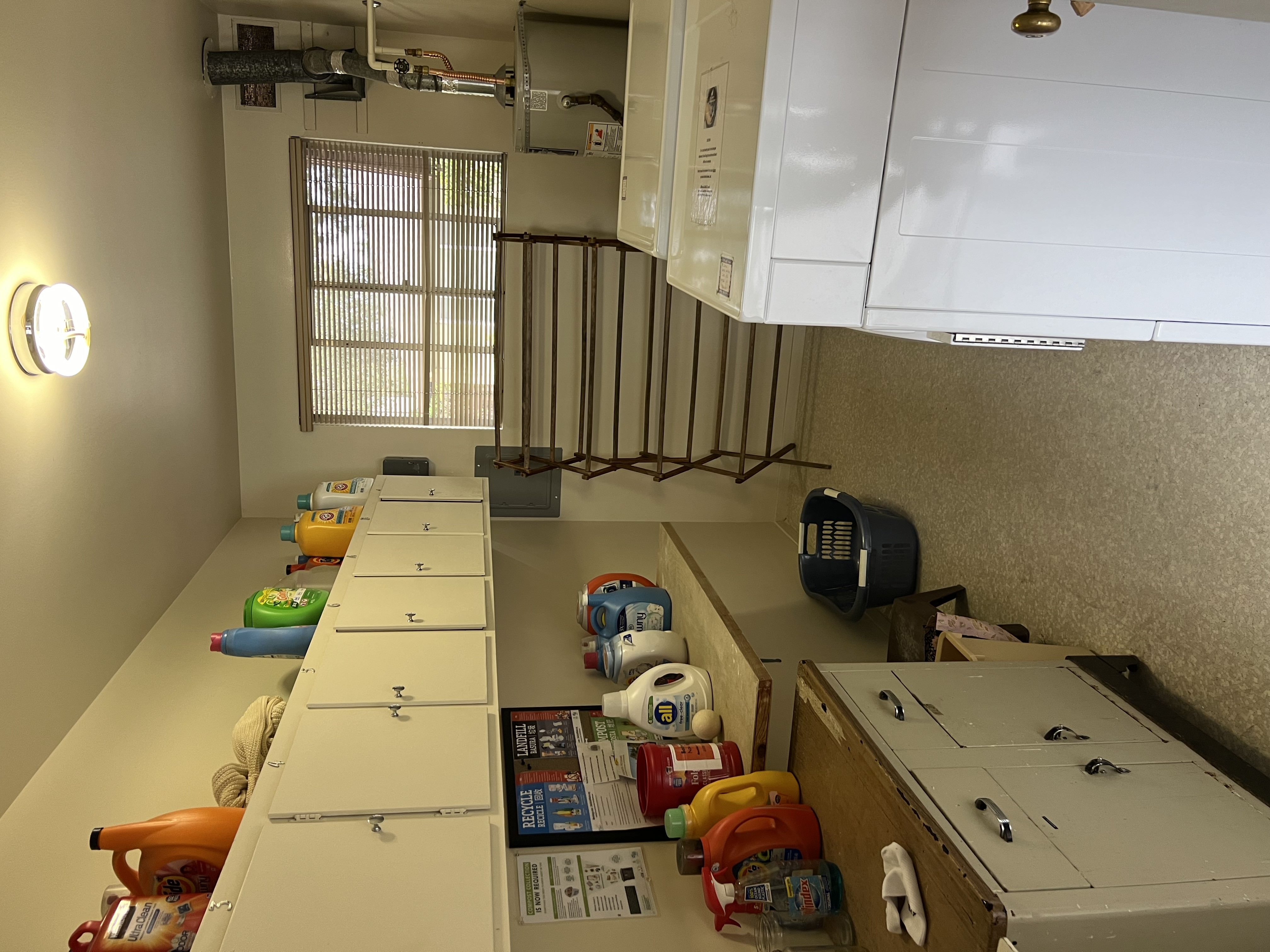 A kitchen with white cabinets and a white counter top with many items on it.
