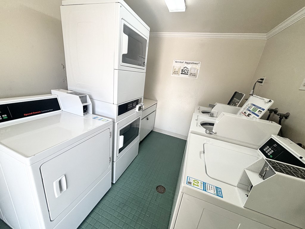 A clean, white-walled commercial kitchen with green floor tiles.