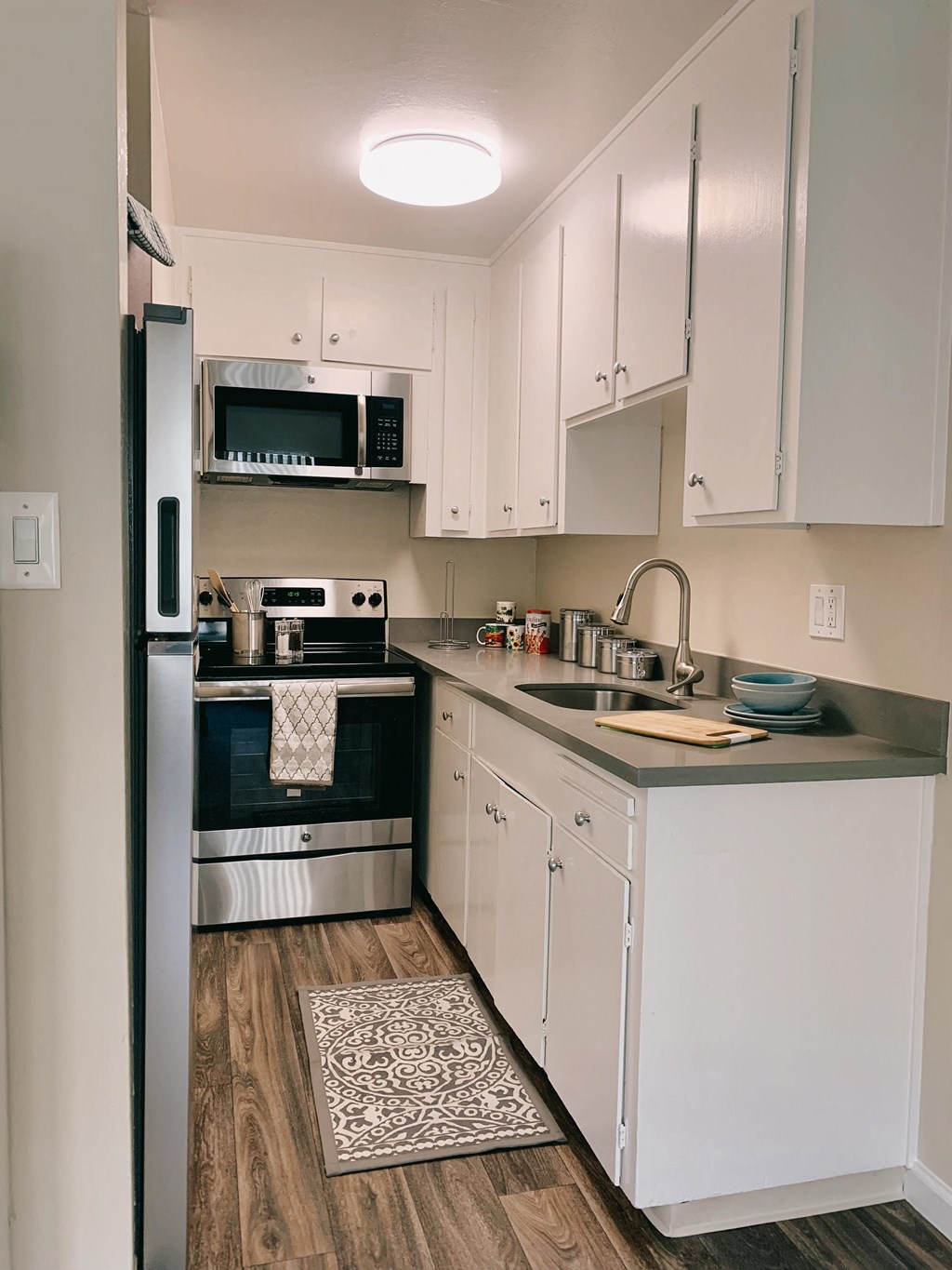 a small kitchen with white cabinets and black appliances