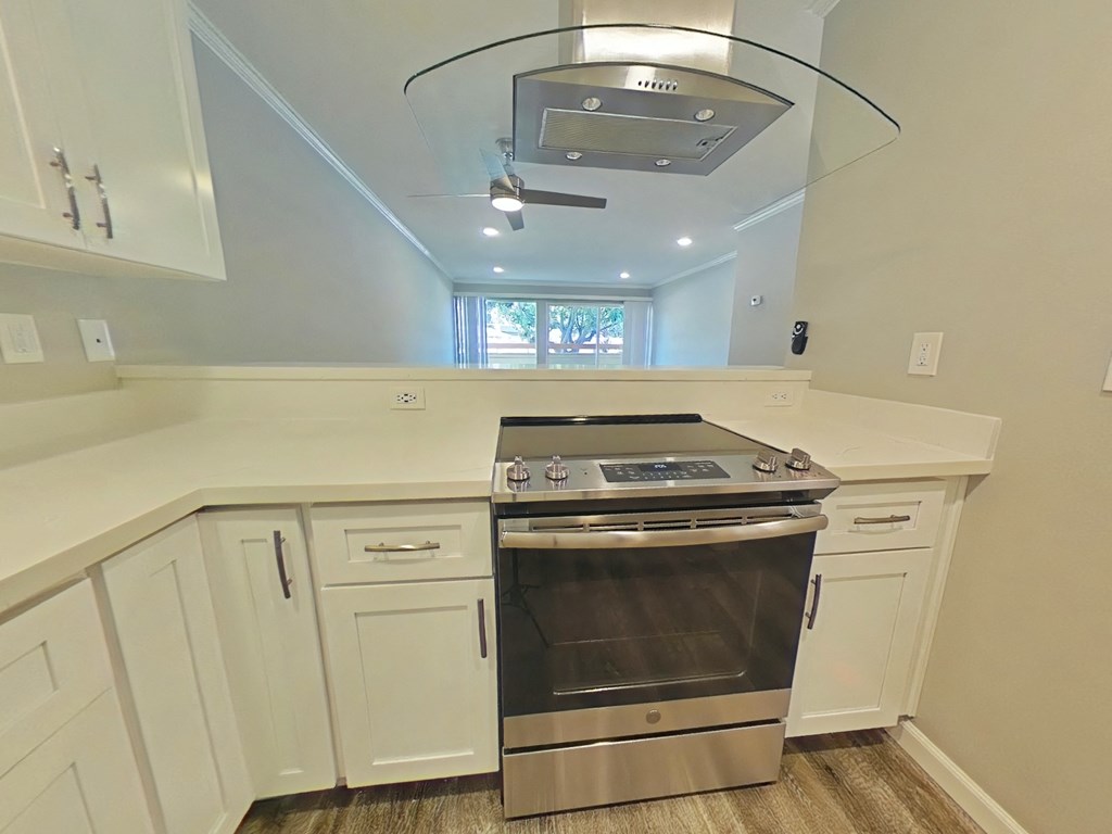 a kitchen with white cabinets and a stove and a ceiling fan