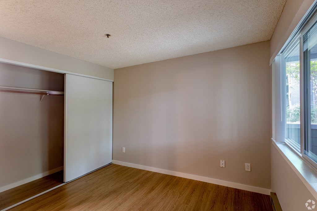 an empty bedroom with a closet and a window