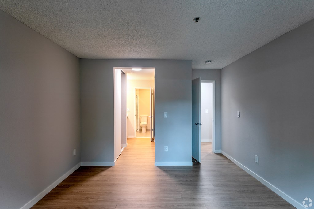 an empty living room and hallway with wood floors and grey walls