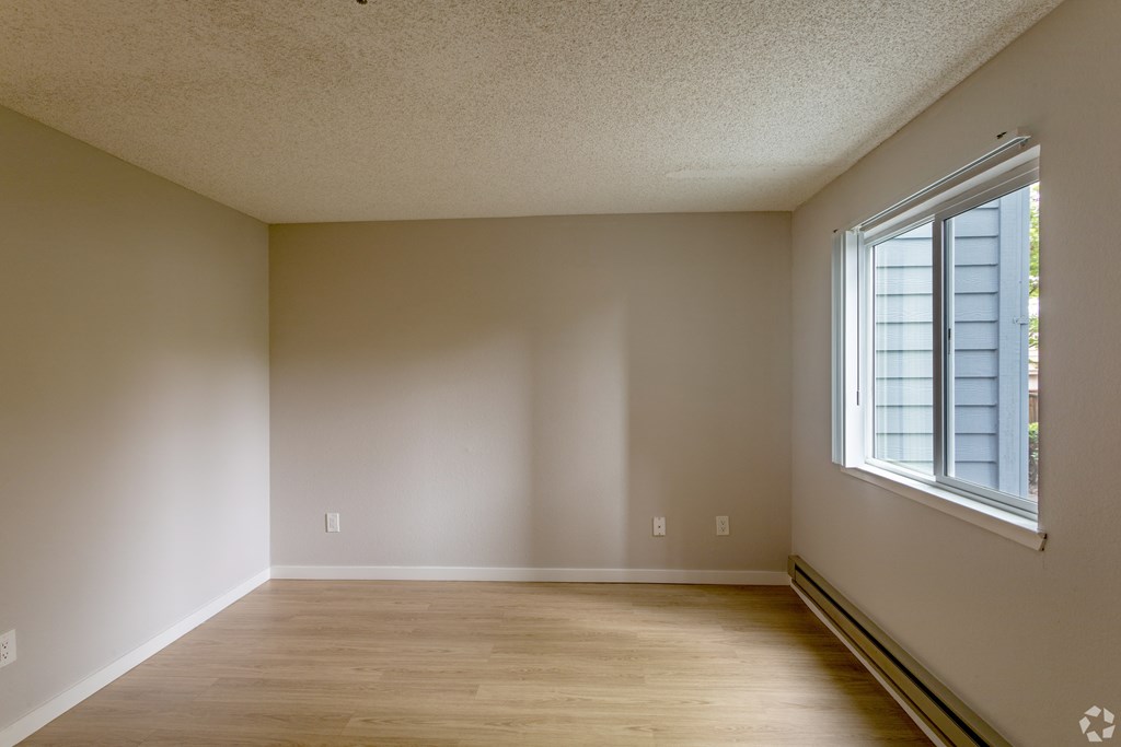 an empty room with wooden floors and a large window