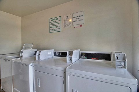 three washing machines are lined up in a laundry room
