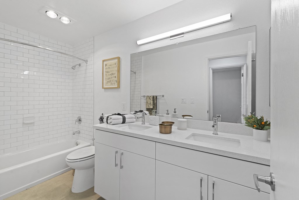 a white bathroom with a large mirror and a white toilet and sink