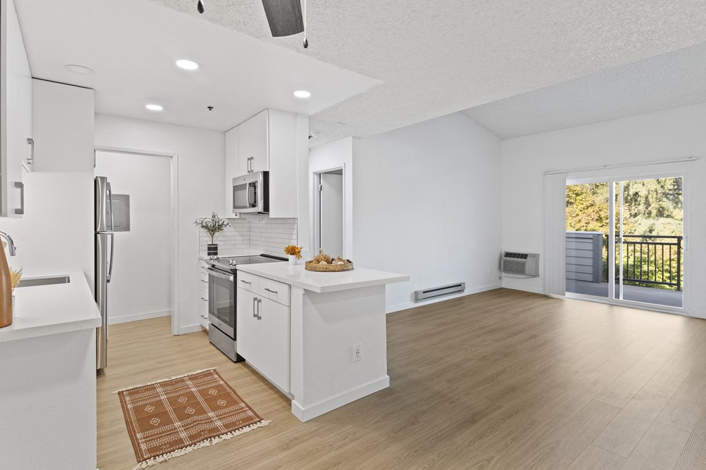 an open kitchen and living room with white walls and wood floors