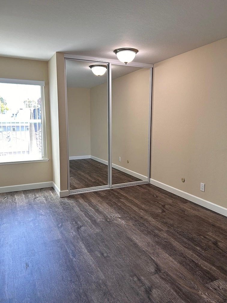 an empty living room with wood floors and a mirrored closet