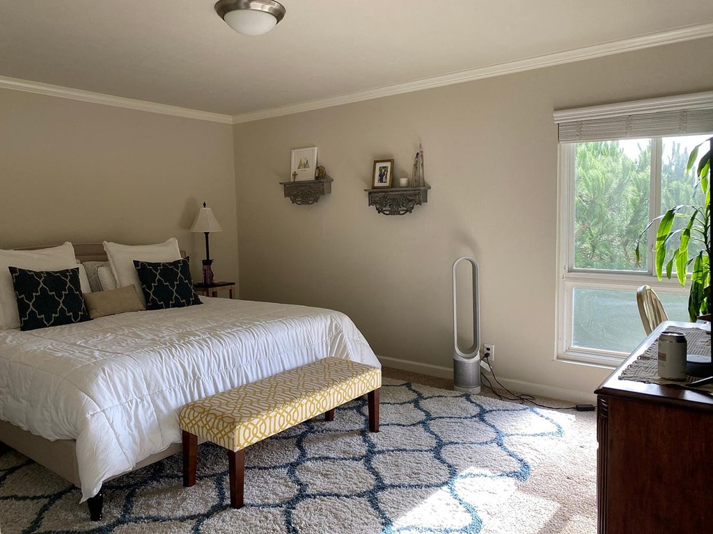 A bedroom with a white bed and a yellow bench.
