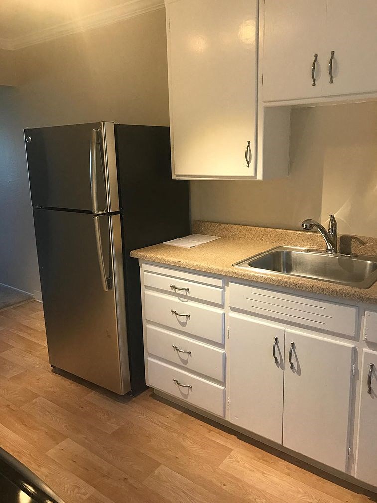 A black refrigerator stands next to a sink in a kitchen.