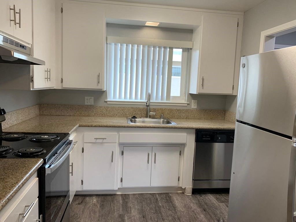 A kitchen with white cabinets and a stainless steel refrigerator.
