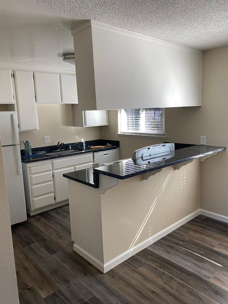A kitchen with a black counter top and white cabinets.