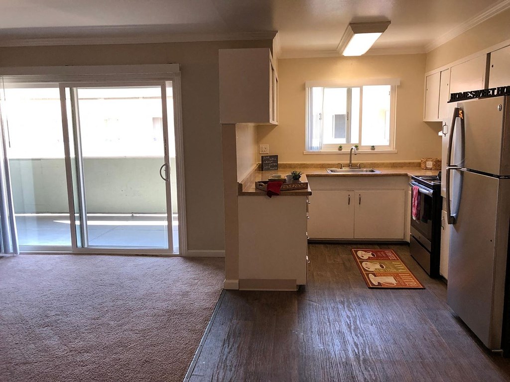 A kitchen with a refrigerator, sink, and cabinets.