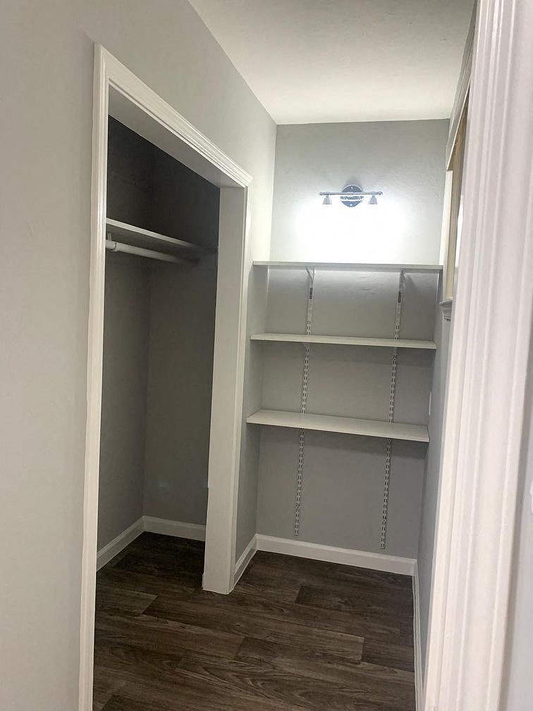 A white closet with a light on and shelves.