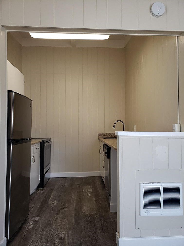 A kitchen with a refrigerator, oven, and sink.