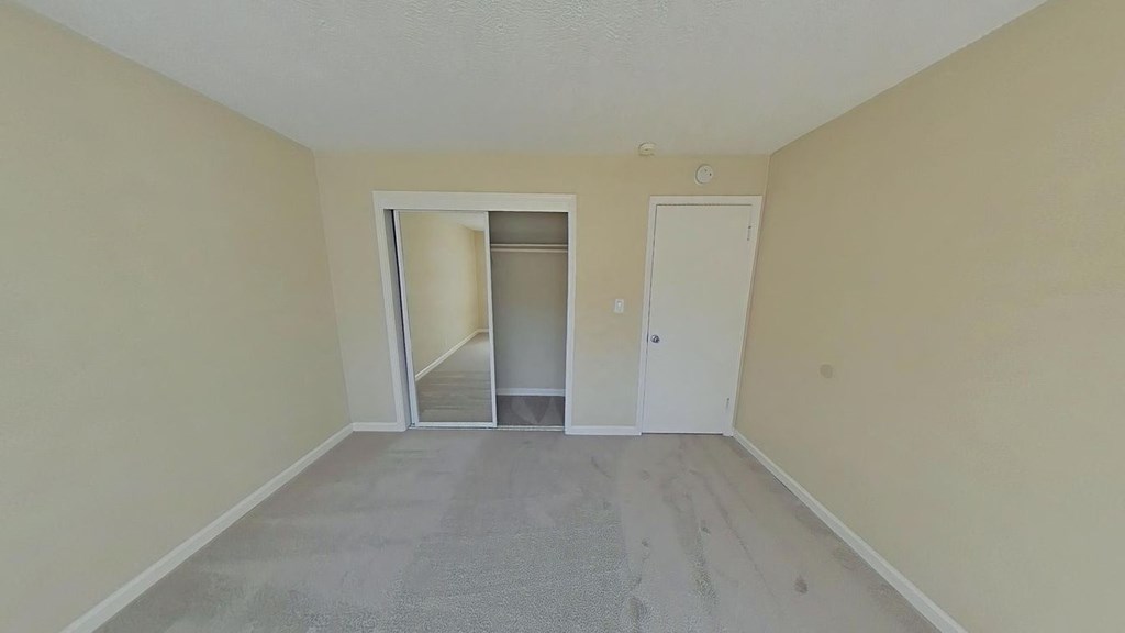 A room with a carpeted floor and two doors, one of which is open.